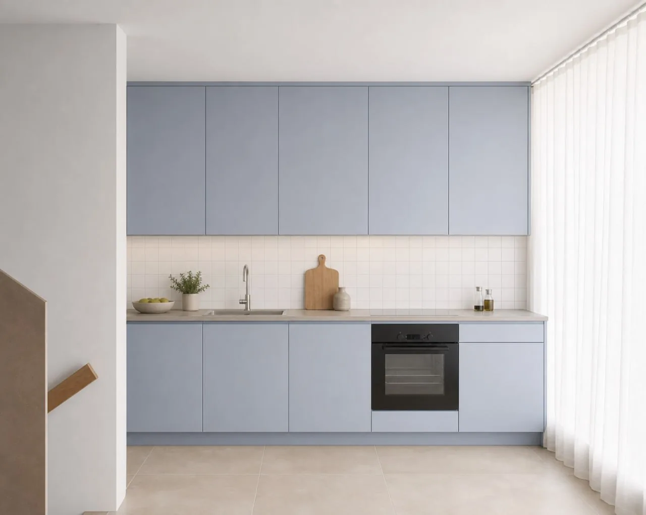 Cuisine linéaire à façades bleu ciel, plan de travail clair et four encastré