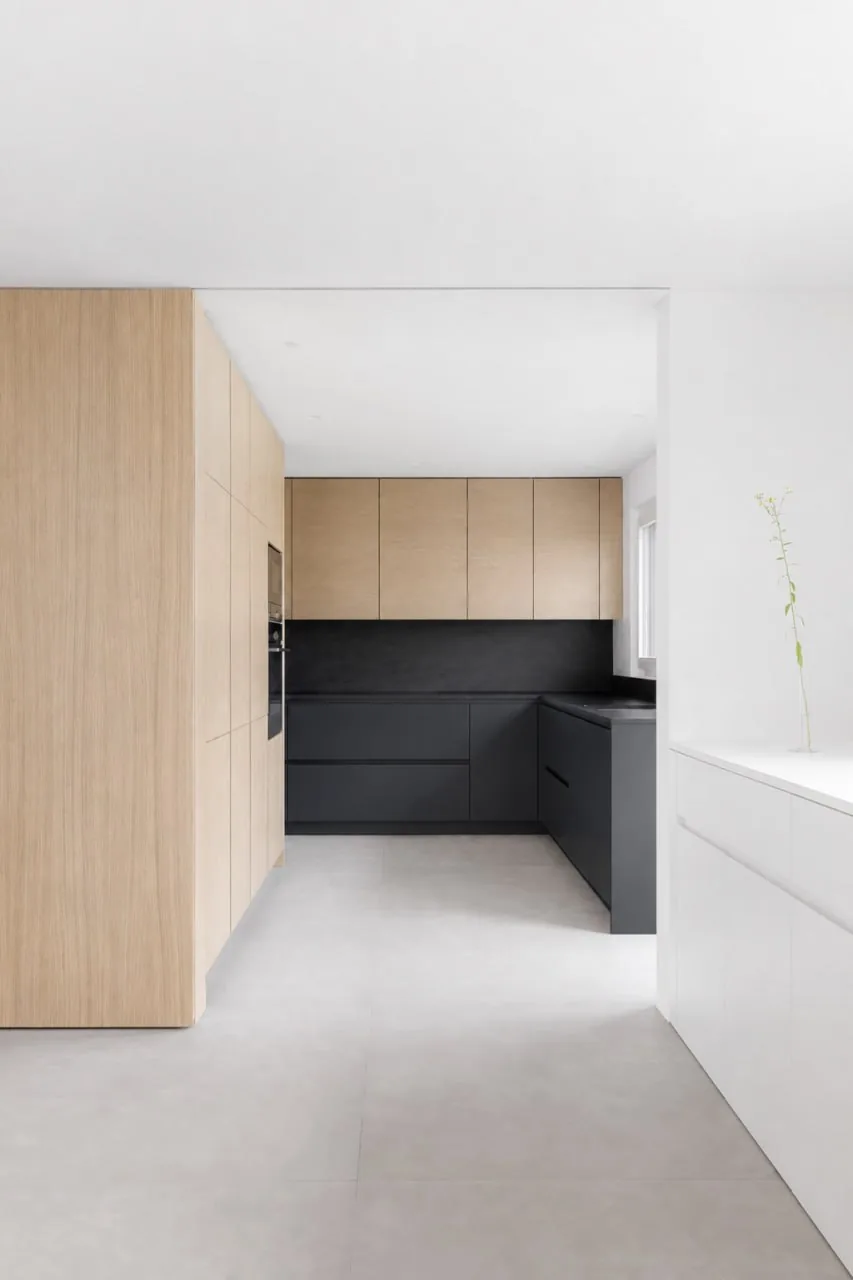 Cuisine à façades noires ouverte sur un couloir en bois clair