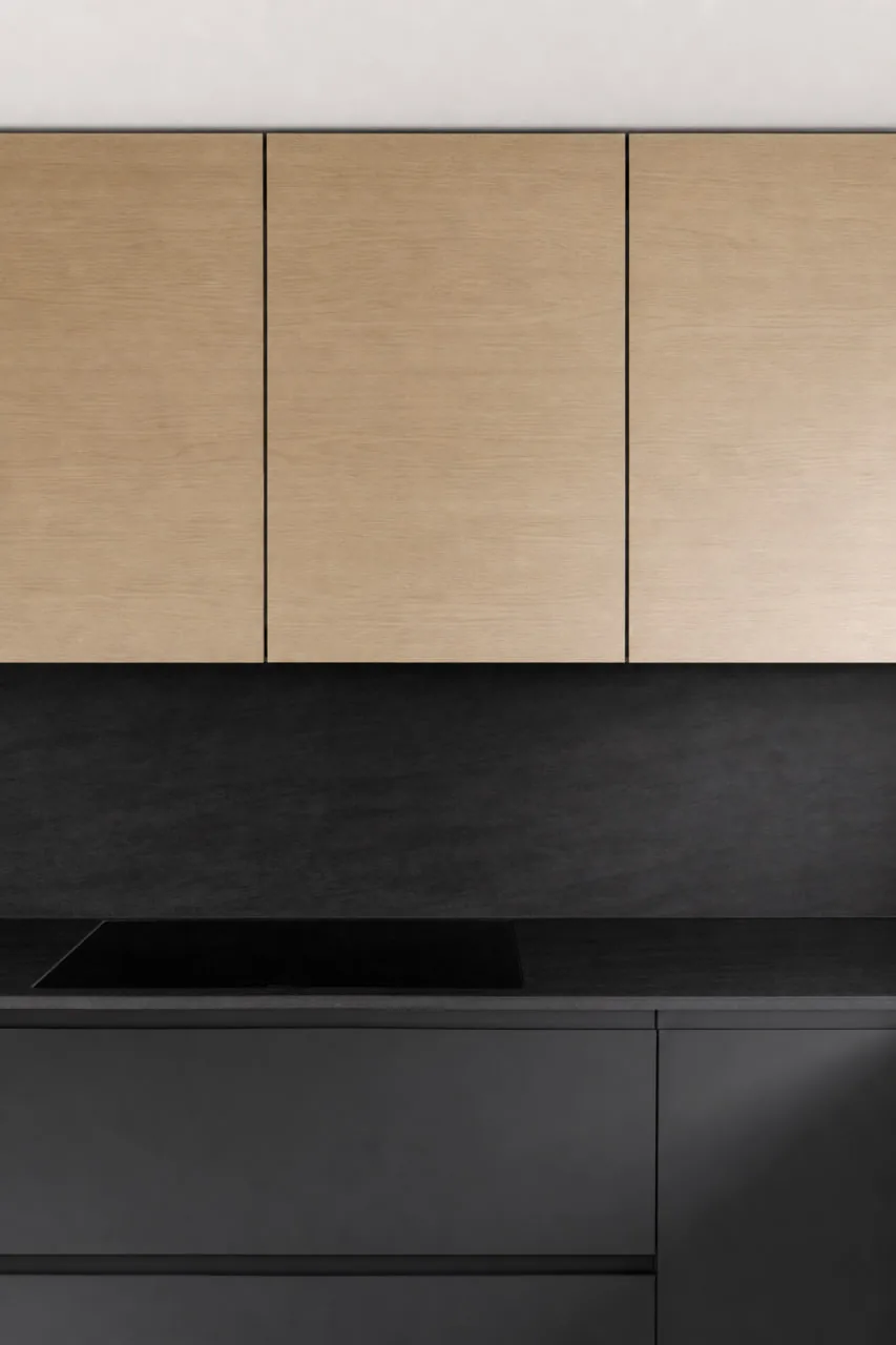 Meuble de cuisine en bois clair surmonté d’un plan de travail noir