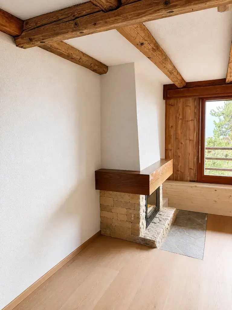 Séjour avec cheminée en pierre, appartement rénové à Verbier